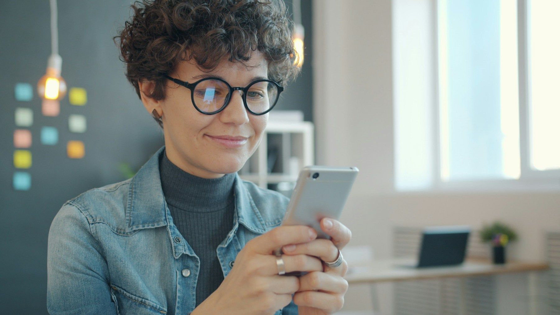 Vendedora sonriendo mientras revisa las ventas del grupo en el celular.